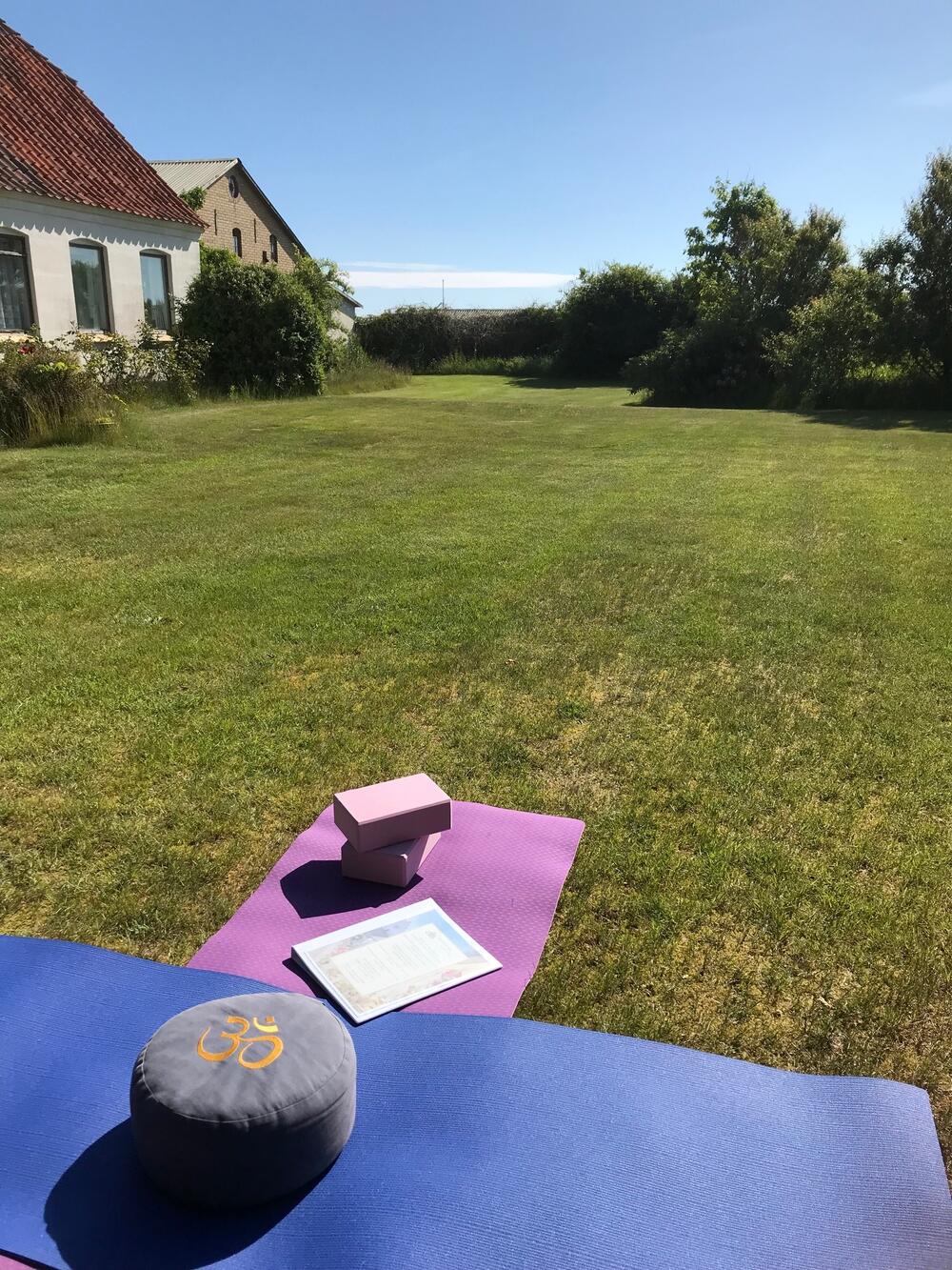 Hagen til gården Havlund, klar med yogamatte, blå himmel og grønt gress
