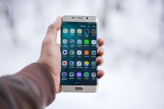 En hånd holder en mobiltelefon med apper