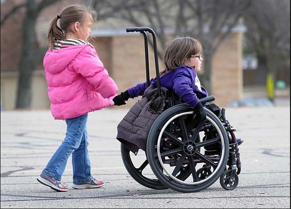 Et barn hjelper et barn i rullestol