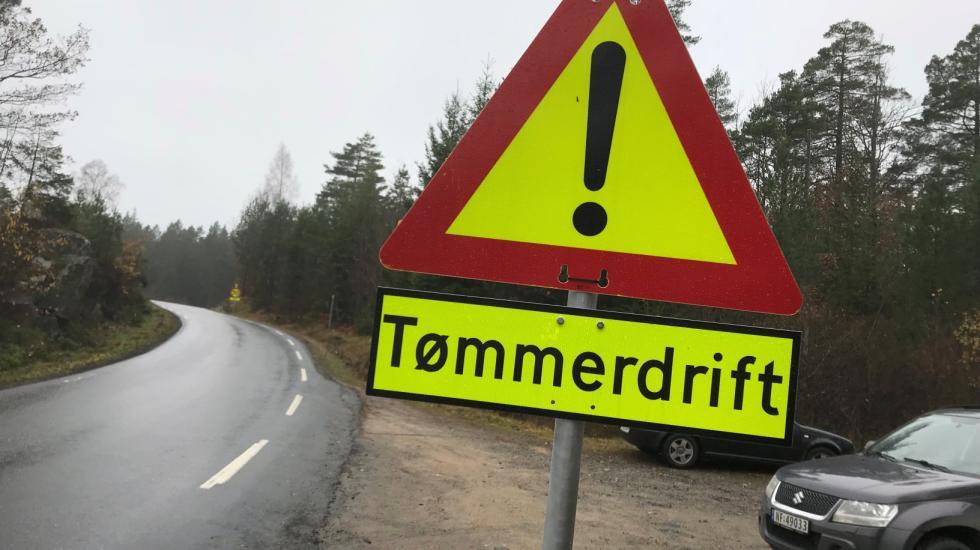 Fotografi av varselskilt med "Tømmerdrift" langs veien.