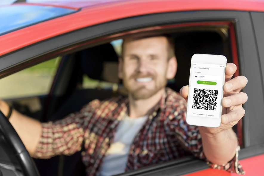 En mann sitter i bilden og viser frem mobil med app for adgangskontroll.