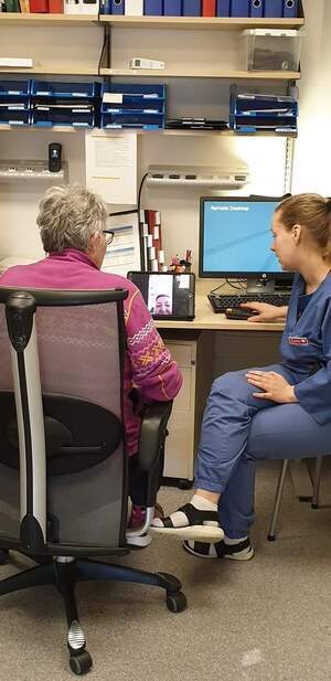 Bilde av en pasient sammen med en pleier, i videosamtale med en pårørende