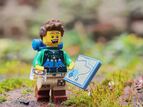 bildet viser en blid LEGO-mann med kart, kompass og ryggsekk