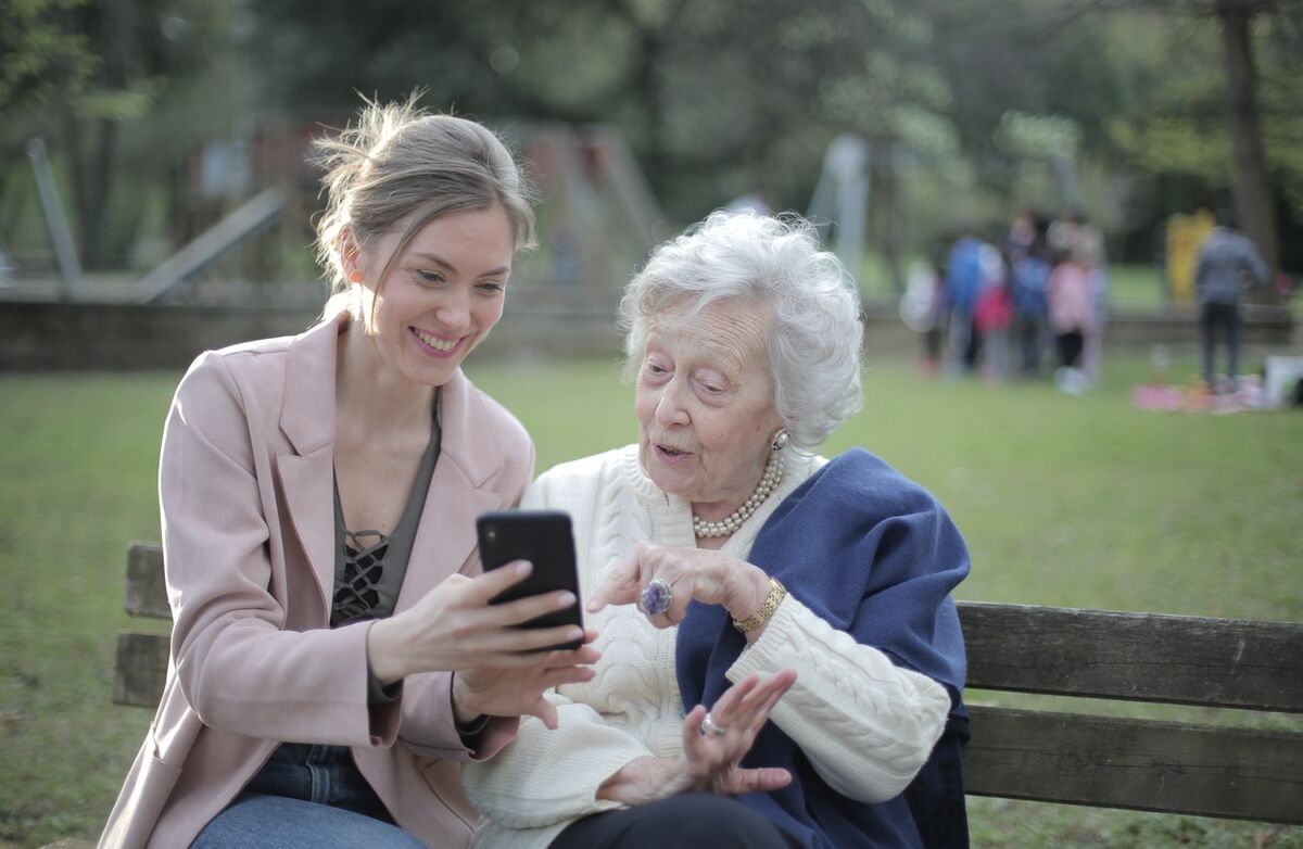 ung kvinne viser eldre kvinne noe på mobil