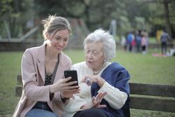 ung kvinne viser eldre kvinne noe på mobil