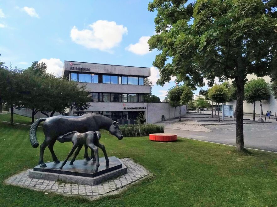 Ås innbyggertorg er et knutepunkt for informasjon, råd og veiledning om kommunens tjenester, og en møteplass som skal fremme samarbeid mellom innbyggere, lag og foreninger, næringsliv og kommunen. Foto: Ås kommune/Ellen M. Ceeberg Oversiktsbilde av fasaden til Ås innbyggertorg, med statuen Hoppe og føll i forkant.