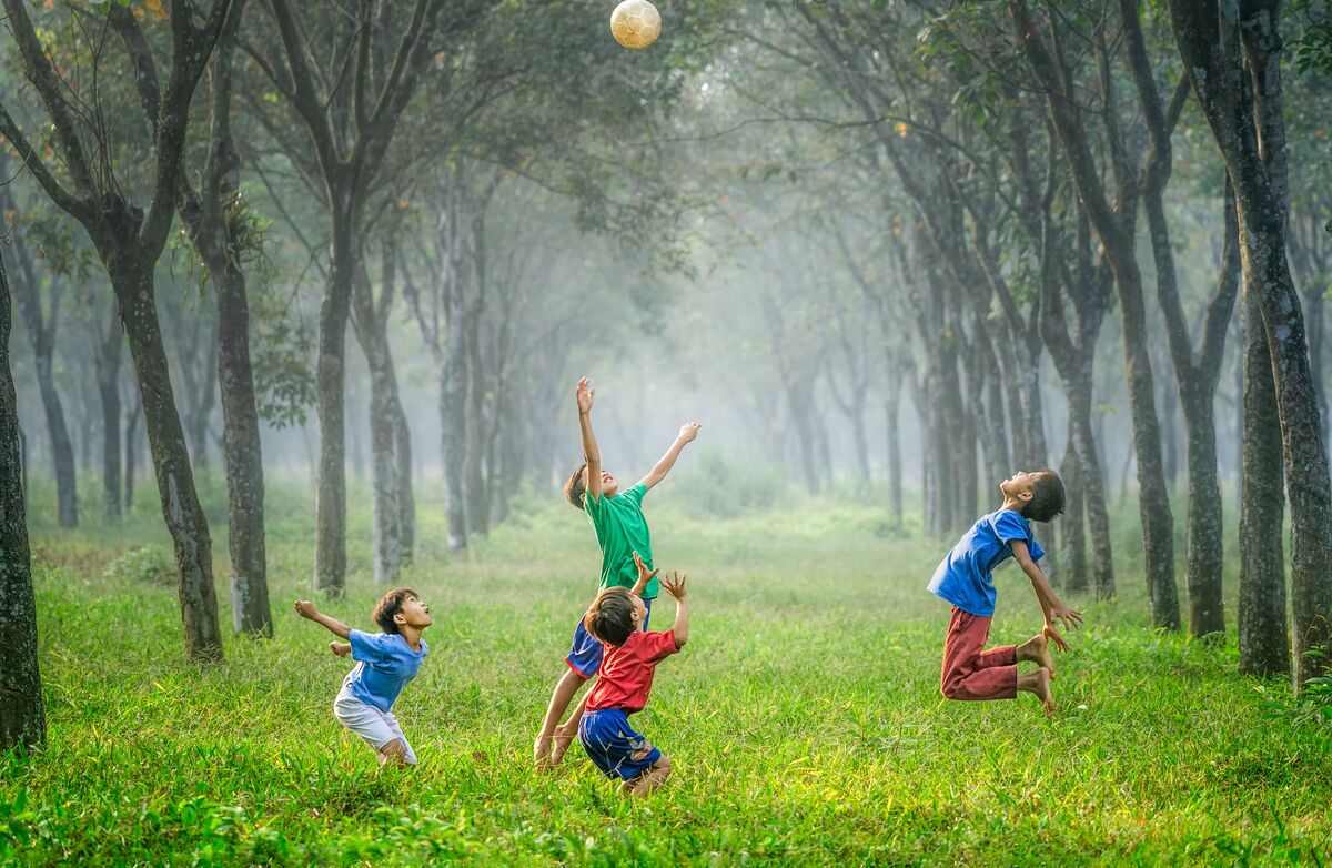 Barn som hopper opp i luften i glede i en stemningsfull skog