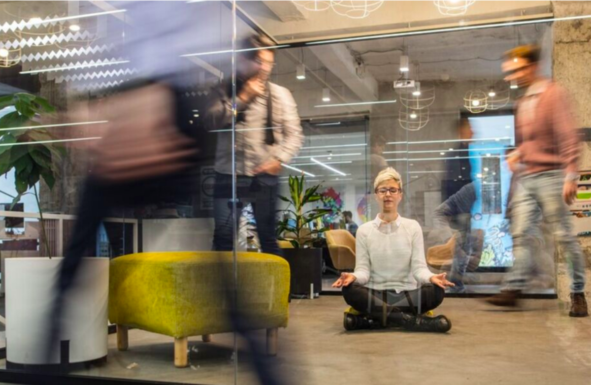 utydelige mennesker i kontormiljø farer forbi. kvinne sitter på gulvet i lotusstilling for meditasjon