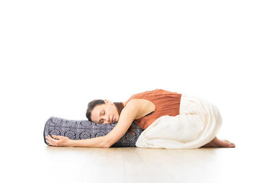 Kvinne hvilende på bolster i yogastudio i barnets stilling, foto