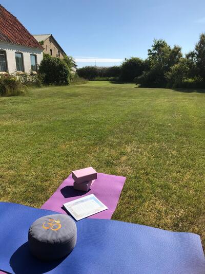 Hagen til gården Havlund, klar med yogamatte, blå himmel og grønt gress