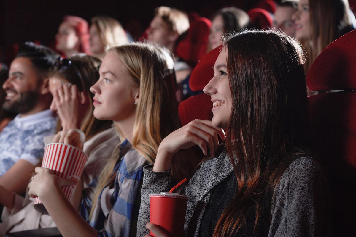 Bilde av unge mennesker på kino, med brus og popcorn.