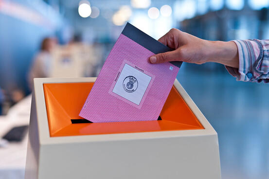 hånd legger stemmeseddel i urne