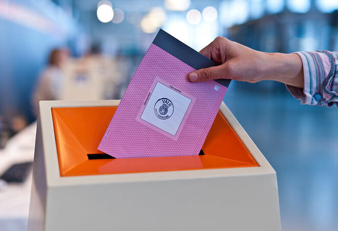 hånd legger stemmeseddel i urne