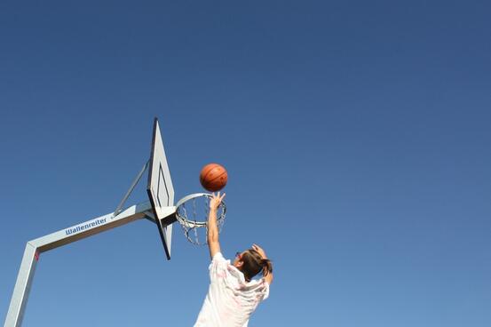 En ungdom som kaster ball mot en basketballkurv