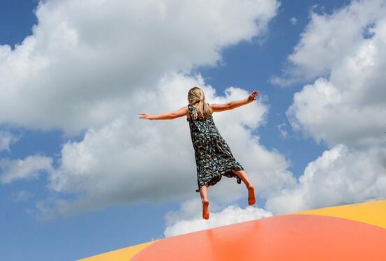 Jente som hopper på en hoppball i strålende sommervær