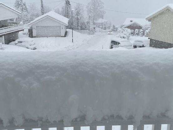 Bilde viser store snømengder på et verandarekkverk og på veger og hus i nabolaget.