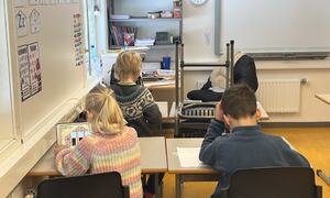 Tre elever på 1. trinn sitter og jobber i klasserommet