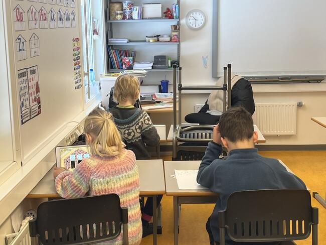 Tre elever på 1. trinn sitter og jobber i klasserommet