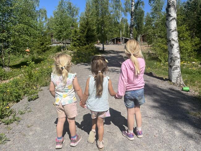 Tre jenter som leier hverandre på tur mot skogen