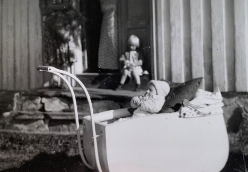 Artikkelforfatteren sitter på trappa til bestemor mens et søskenbarn låner barnevogna. (Foto: Privat)