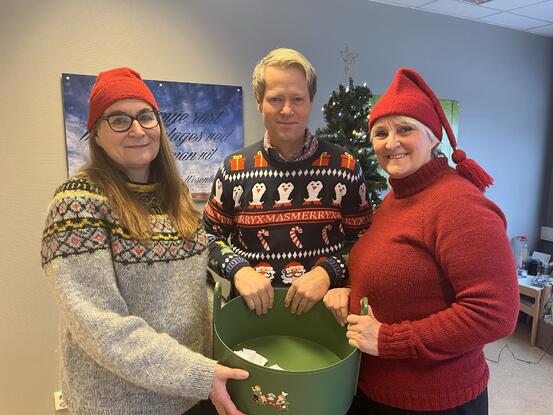 Mona Haugen, Harald Tyrdal og Toril Svendsbråten er julepyntet og holder en bolle med lapper som skal trekkes.