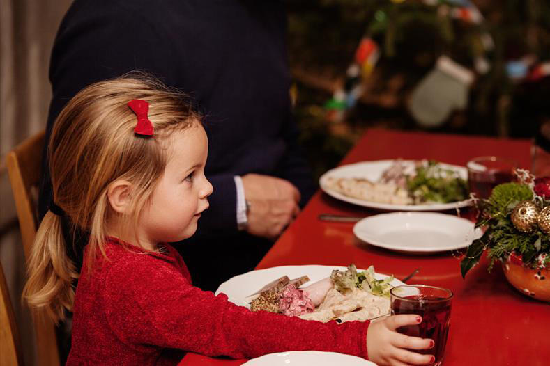 Jente som sitter ved et julepyntet bord