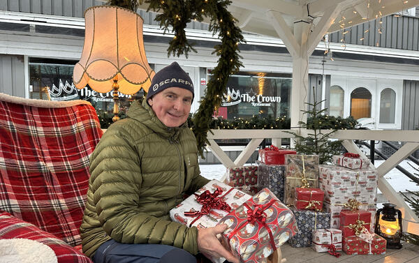 Mann i dunjakke som holder julegaver