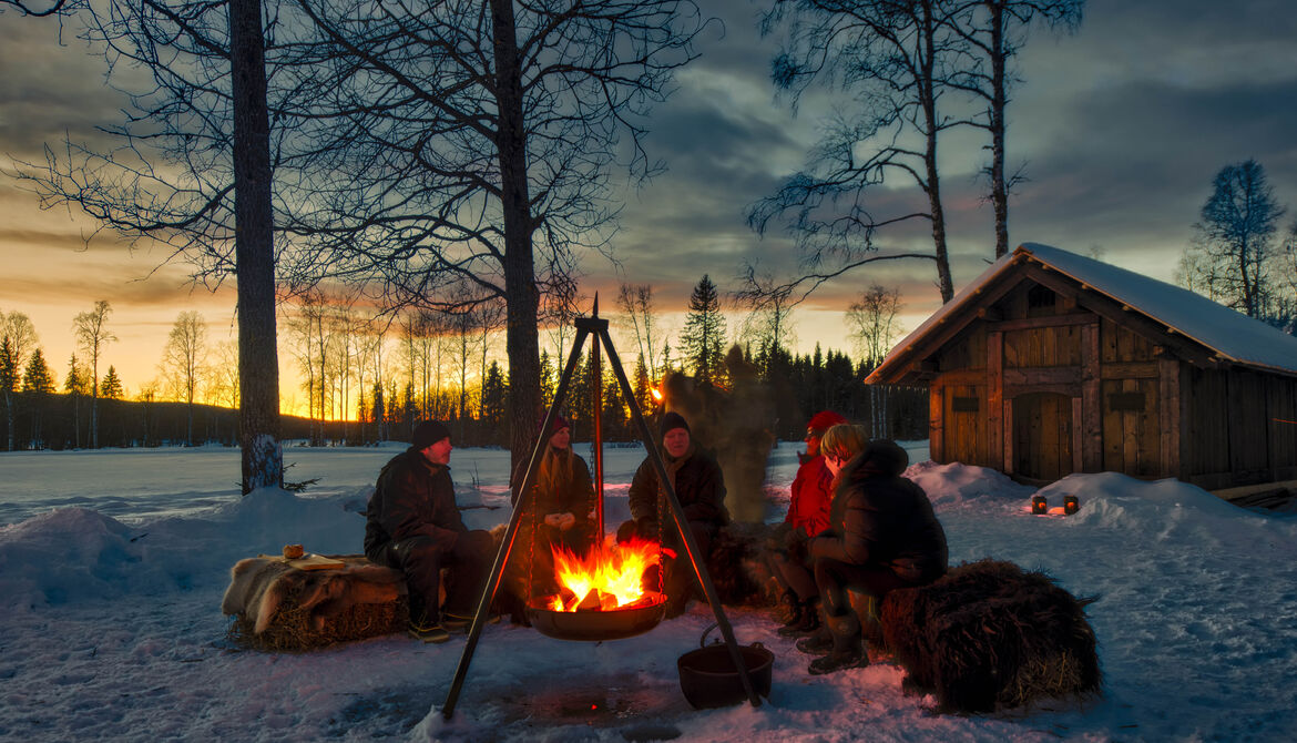 Bilde av en gruppe mennesker rundt et bål om vinteren