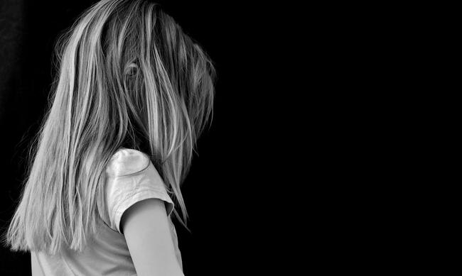 Svart hvitt bilde med profilbilde av jente med langt hår mot mørk bakgrunn