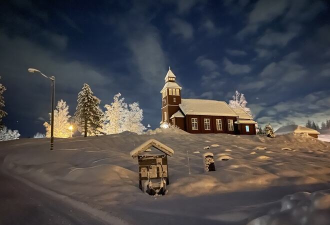 Grua kirke og området rundt kirken. Vinterbilde tatt om kvelden.