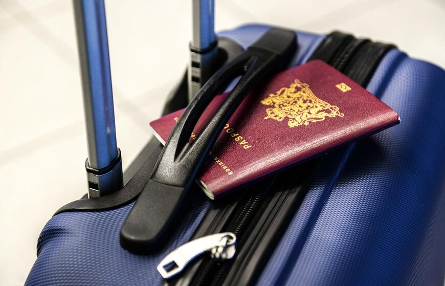 Bilde av en koffert og et pass som ligger på toppen av kofferten