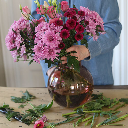 En flott bukett med tre ulike blomster i rosa-toner settes i vase