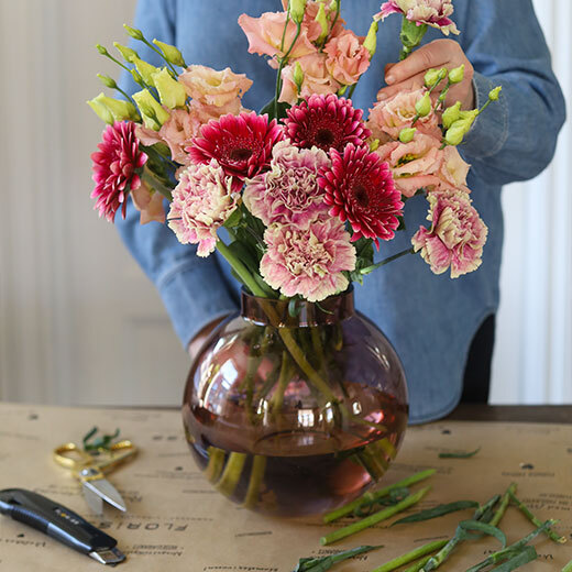 En flott bukett med tre ulike blomster i rosa- og ferskentoner settes i vase