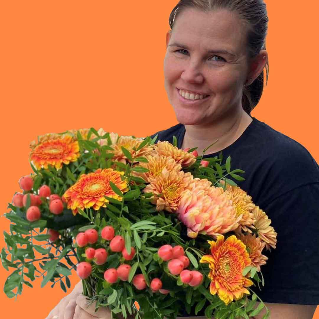 En av våre fantastiske kvinnelige ansatte som holder en bukett med oransje blomster