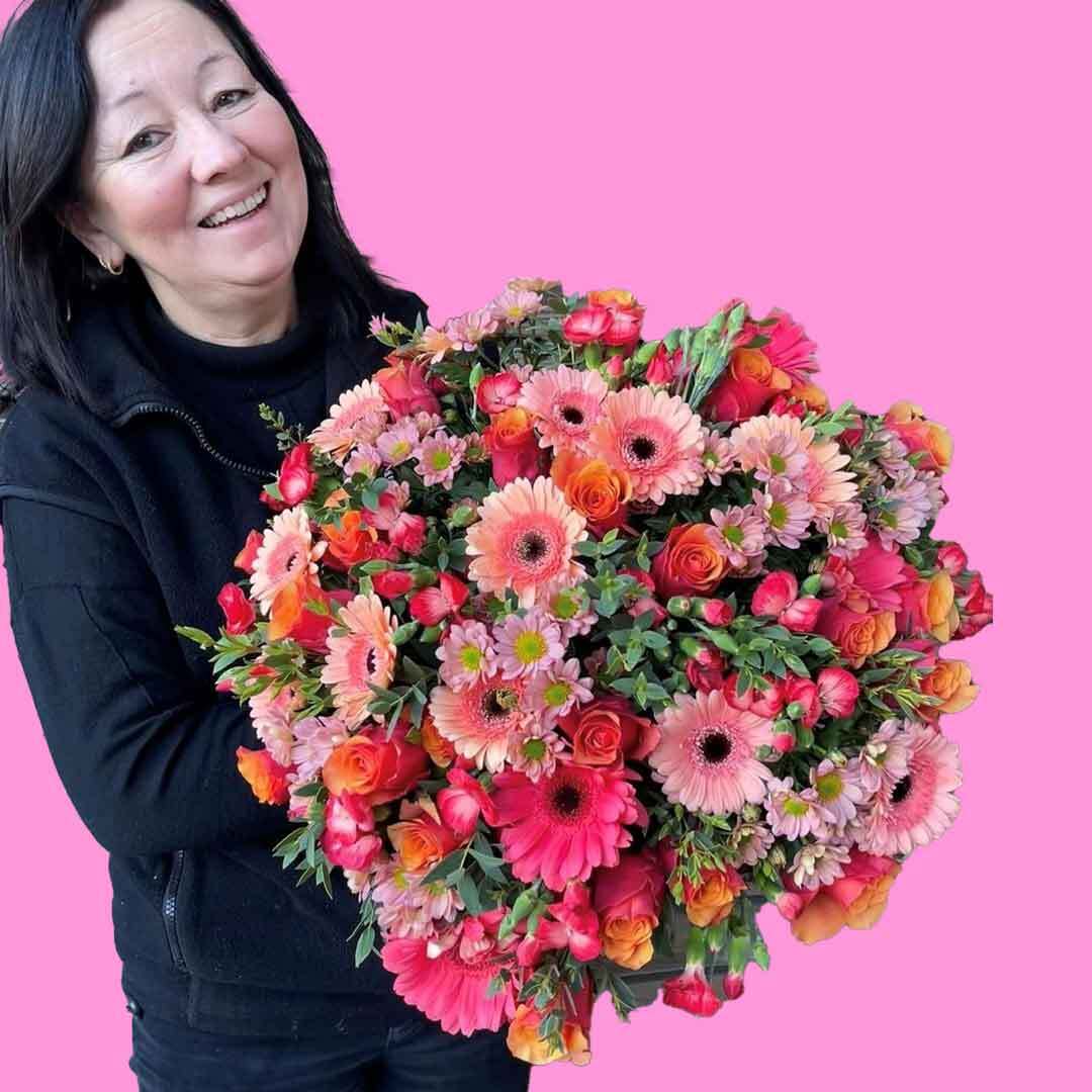En av våre fantastiske kvinnelige ansatte som holder en bukett med rosa blomster