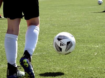 Nærbilde av ben som sparker ball på en fotballbane