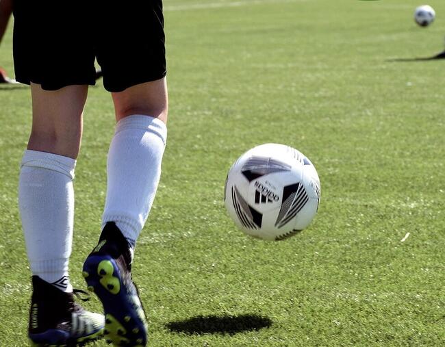 Nærbilde av ben som sparker ball på en fotballbane