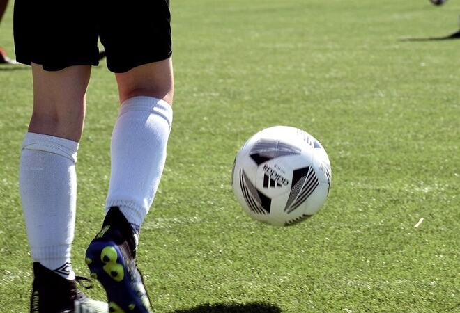 Nærbilde av ben som sparker ball på en fotballbane