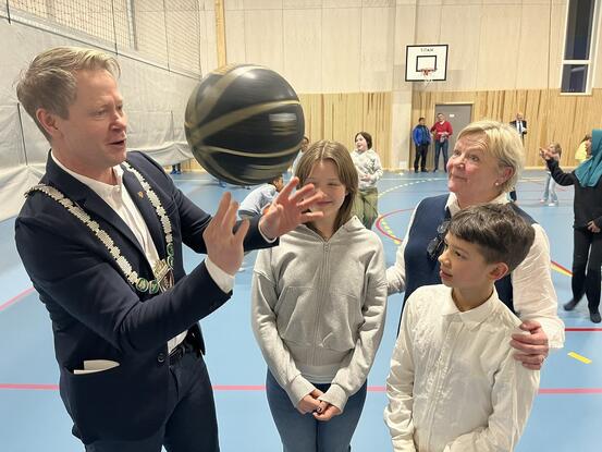 Harald trikser med ball mens rektor Grete Monsrud Sandvik og leder og nestleder i elevrådet ser på.