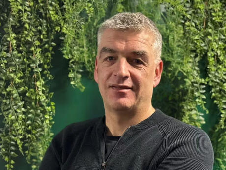 Mann med grått hår og grønn plantebakgrunn