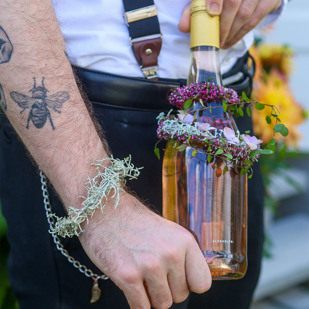 Blomsterpynt festet til flaske og armbånd laget av lyng