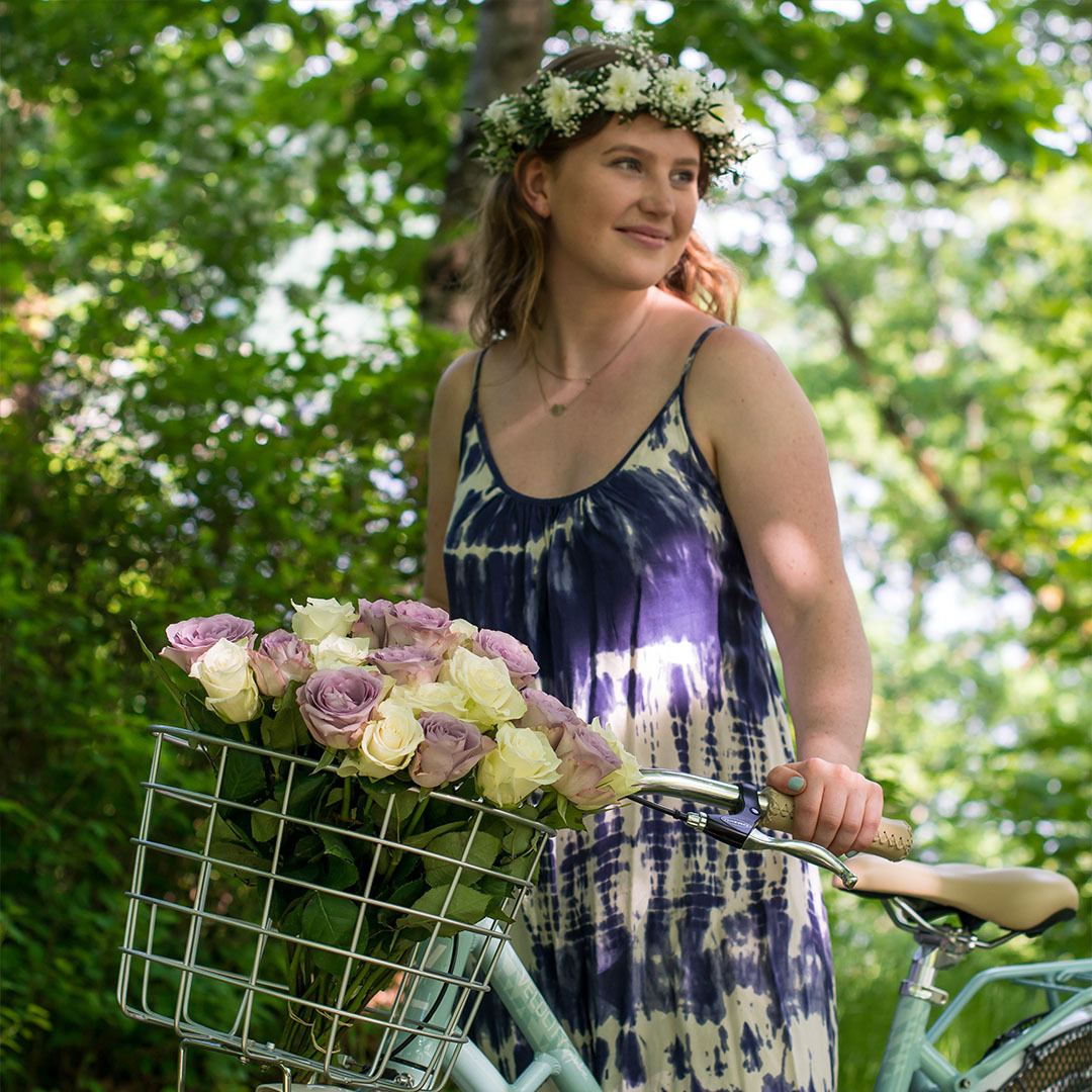 Blomsterkrans og en bukett med sommerlige roser i sykkelkurven