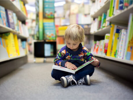 Barn på gulvet med bok på et bibliotek