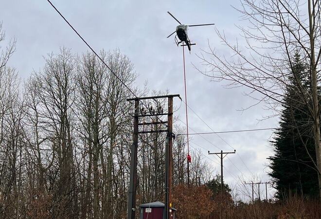 Helikopter i lav høyde over høyspentmaster