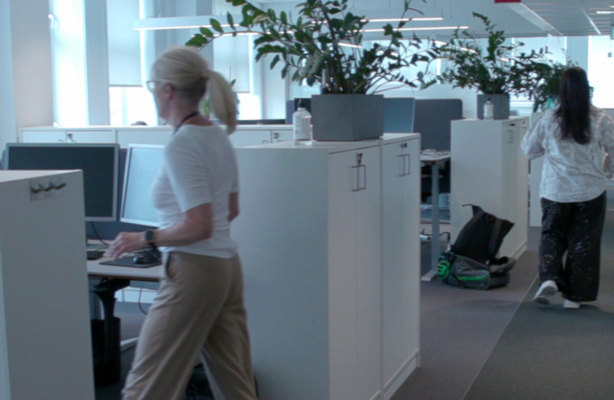 Kontorløsningen kan påvirke både hvordan vi jobber og hvordan vi har det på jobb. Foto: stami.no To kvinner i et kontorlandskap, der vi ser noen planter og en del arkivskap, et par PCer