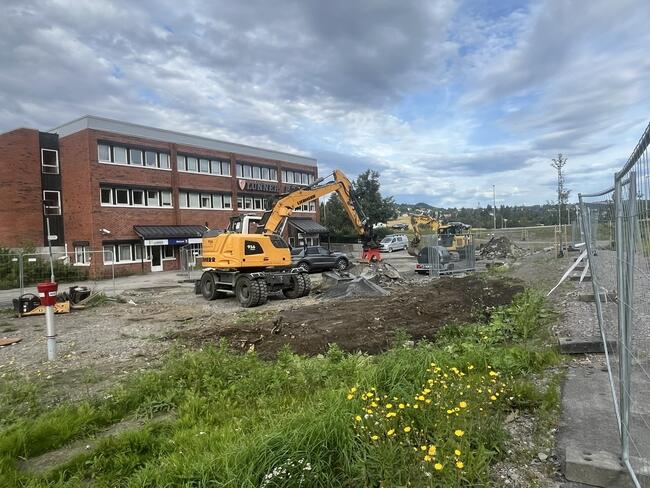 To gravemaskiner som jobber på parkeringsplassen foran rådhuset