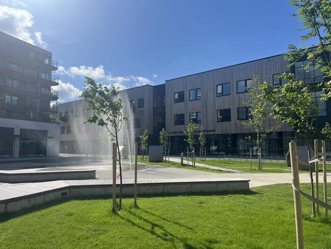 Torget på Harestua om sommeren med inngangen til Lunner helse- og omsorgssenter i bakgrunnen