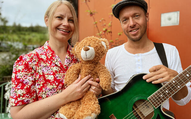 Prøysenhusets formidlere utendørs med bamse og gitar