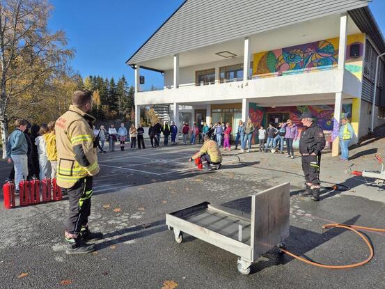 Barn utenfor skolen som ser på brannmenn demonstrerer slukningsustyr