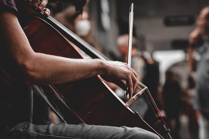 Nærbilde av person som spiller cello. Du ser personens arm og hånden som holder buen når hen spiller cello.